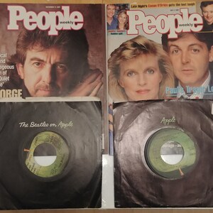 Pode incluir: Duas edições da revista People Weekly são exibidas, uma com George Harrison e outra com Paul McCartney. Abaixo de cada revista estão discos de vinil em capas pretas, rotulados como "The Beatles on Apple."