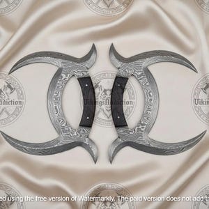 May include: Two curved, Damascus steel blades with black handles. The blades have a unique pattern and are arranged symmetrically. The background is a light-colored, textured fabric. The text "VikingsAddiction" is visible.