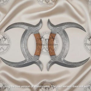 May include: Two curved, Damascus steel blades with wooden handles, arranged symmetrically. The blades have a unique pattern and are set against a cream-colored, textured background. The logo "VikingsAddiction" is visible.
