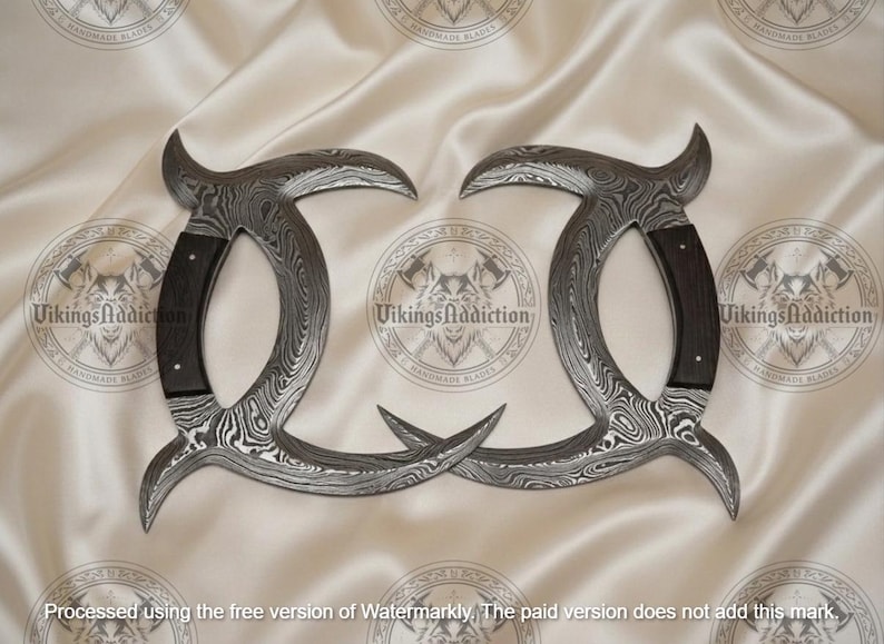 May include: Two curved, Damascus steel blades with dark wood handles. The blades have a unique pattern and are arranged symmetrically against a cream-colored background. The text "VikingsAddiction" is visible.