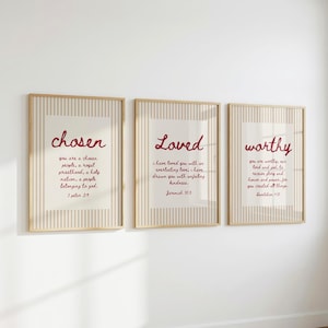 Könnte beinhalten: Drei gerahmte Wandbilder mit hellbeigem Hintergrund und vertikalen weißen Streifen. Jeder Druck zeigt dunkelroten kursiven Text mit Bibelversen: chosen 1 Peter 2:9, Loved Jeremiah 31:3 und worthy Revelation 4:11.