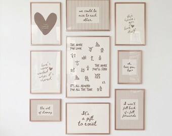 May include: A gallery wall set of nine framed prints with rose gold frames. The prints feature various handwritten quotes, a large heart, and small line-art figures on cream backgrounds, some with vertical striped patterns and others with plain backgrounds.