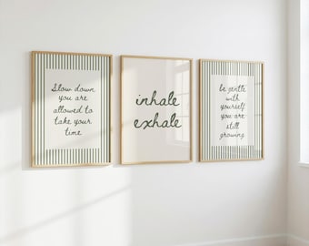 May include: Three framed wall art prints with light wood frames. The left and right prints feature green and white vertical stripes with the text "Slow down you are allowed to take your time" and "be gentle with yourself you are still growing". The center print has the text "inhale exhale".
