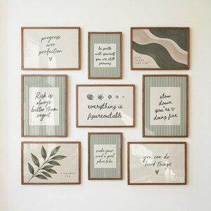 May include: A gallery wall set of nine framed prints with wooden frames. The prints feature sage green striped backgrounds, botanical illustrations, and motivational text including "progress over perfection" and "everything is figureoutable."