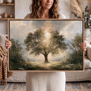 May include: A rectangular framed wall art print featuring an oil painting of a large, central oak tree in a meadow. Sunlight streams through the branches, creating a radiant glow against a soft, cloudy sky. The landscape includes muted green foliage.