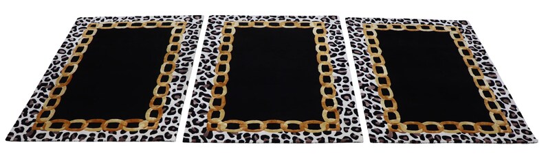 May include: Three rectangular rugs featuring a solid black centre, a gold-toned chain link border, and an outer edge with a black and white leopard print pattern. The rugs are arranged side-by-side, displaying a consistent design across all pieces.