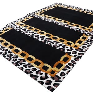 May include: A rectangular rug featuring a central solid black panel framed by a gold-coloured chain link border. The outer edge of the rug displays a repeating black, white, and grey leopard print pattern that surrounds the entire central design.