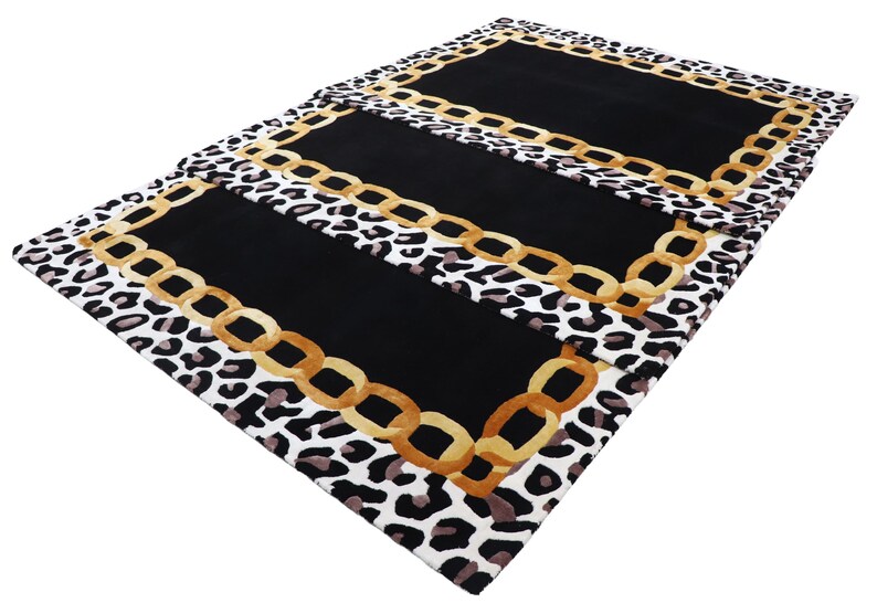 May include: A rectangular rug featuring a central solid black panel framed by a gold-coloured chain link border. The outer edge of the rug displays a repeating black, white, and grey leopard print pattern that surrounds the entire central design.