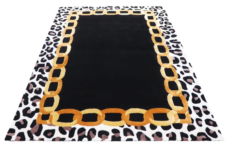 May include: A rectangular area rug featuring a solid black centre panel, a wide border composed of interlocking golden-yellow chain links, and an outer edge patterned with a black and white leopard print design on a white background.