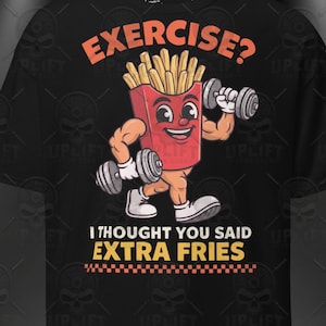 Könnte beinhalten: Ein schwarzes T-Shirt mit einer Cartoon-Grafik einer roten Pommes-Frites-Schachtel mit muskulösen Armen, die graue Hanteln heben. Der Text darüber lautet EXERCISE? und der Text darunter lautet I THOUGHT YOU SAID EXTRA FRIES mit einem Karomuster.