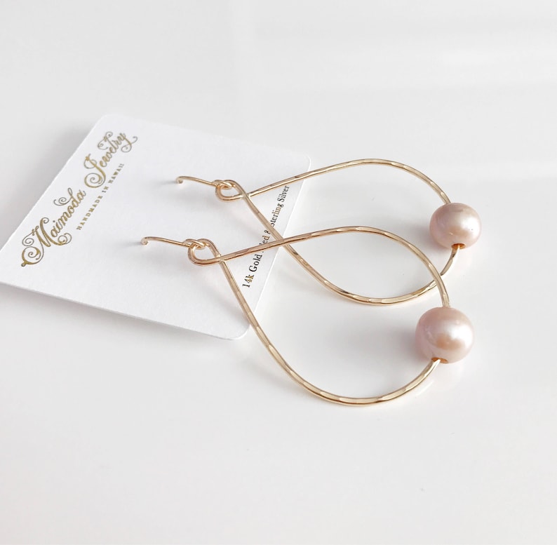 May include: Gold teardrop earrings with a pearl accent. The earrings are handmade and feature a 14k gold filled wire.