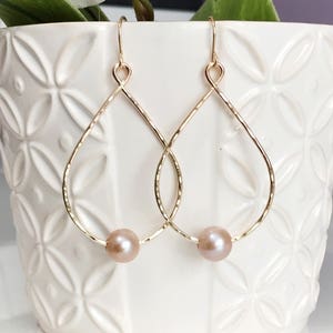 May include: Gold teardrop earrings with a single pearl on each earring.