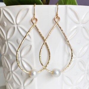 May include: Gold teardrop earrings with a single pearl accent on each earring.