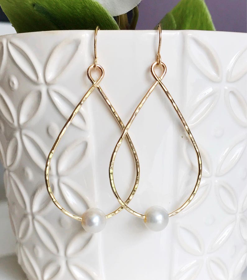 May include: Gold teardrop earrings with a single pearl accent on each earring.