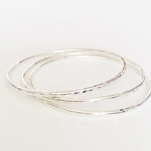 Peut inclure: Trois bracelets en argent avec une texture martel&eacute;e. Les bracelets sont empil&eacute;s les uns sur les autres.