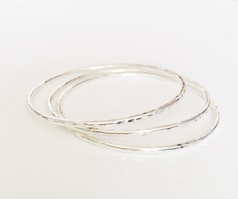 Peut inclure: Trois bracelets en argent avec une texture martel&eacute;e. Les bracelets sont empil&eacute;s les uns sur les autres.