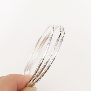 Peut inclure: Ensemble de quatre bracelets en argent martel&eacute;. Les bracelets sont empil&eacute;s les uns sur les autres, cr&eacute;ant un look superpos&eacute;.