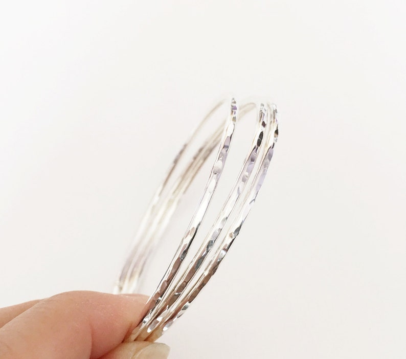 Peut inclure: Ensemble de quatre bracelets en argent martel&eacute;. Les bracelets sont empil&eacute;s les uns sur les autres, cr&eacute;ant un look superpos&eacute;.