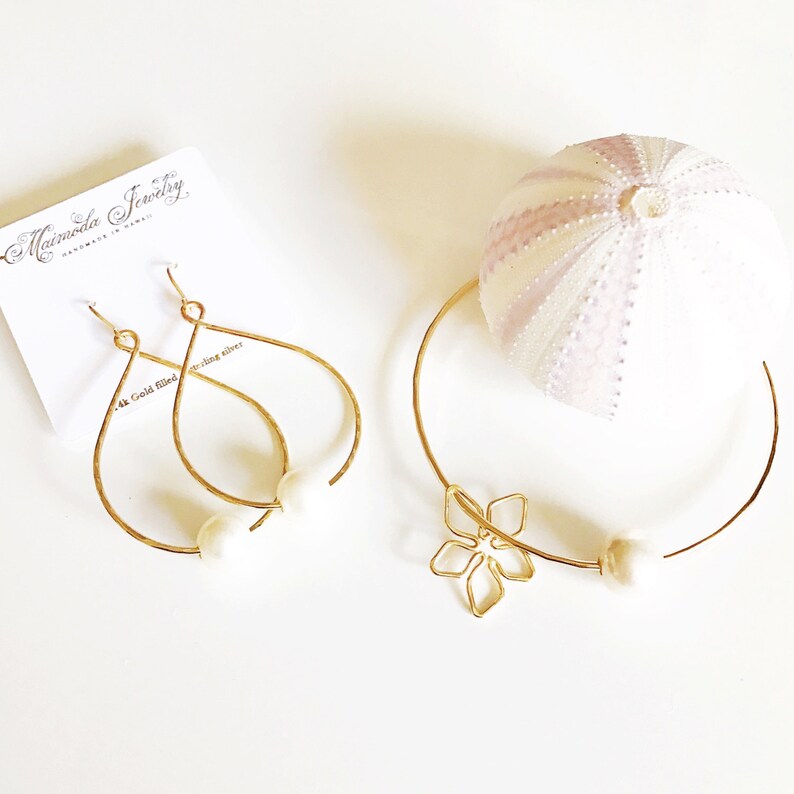 May include: Gold filled earrings and a gold filled choker necklace with a flower charm. Both pieces feature a white pearl accent.