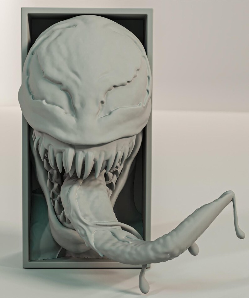 Pu&ograve; includere: Una scultura grigia stampata in 3D di una testa mostruosa con denti affilati e una lunga lingua estesa. La testa &egrave; inserita in una cornice rettangolare e il design generale ha un aspetto strutturato e organico.