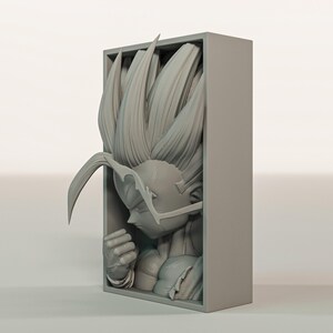 Puede incluir: Una escultura gris impresa en 3D de un personaje con pelo puntiagudo, dentro de un marco rectangular. La figura est&aacute; en una pose contemplativa, con el pu&ntilde;o cerrado y rasgos faciales detallados. Es un objeto de colecci&oacute;n.
