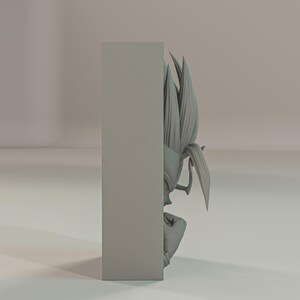 Puede incluir: Una escultura gris impresa en 3D de un personaje con pelo puntiagudo y una expresi&oacute;n decidida. La figura est&aacute; parcialmente oscurecida por un bloque rectangular, creando una composici&oacute;n visual &uacute;nica. La escultura es probablemente un objeto de colecci&oacute;n o decorativo.