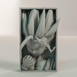 Puede incluir: Una escultura gris tridimensional de un personaje con cabello puntiagudo y una expresi&oacute;n decidida, enmarcada en un marco rectangular. El pu&ntilde;o de la figura est&aacute; cerrado y los detalles est&aacute;n finamente representados.