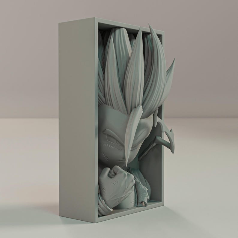 Puede incluir: Escultura gris impresa en 3D de un personaje con pelo puntiagudo y expresi&oacute;n decidida, dentro de un marco rectangular. El pu&ntilde;o cerrado y los rasgos faciales detallados de la figura son prominentes. Una obra de arte coleccionable.