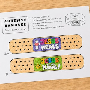 May include: A printable paper craft sheet for adhesive bandage bracelets featuring instructions and two colored designs. One design reads Jesus Heals with a heart and cross, and the other reads Jesus Is My King with a crown. The sheet includes scissors icons.