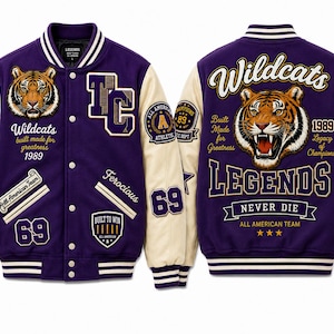 Könnte beinhalten: Eine lila-cremefarbene Collegejacke mit einem Tiger-Motiv und den Schriftzügen "Wildcats" und "Legends". Die Jacke hat Aufnäher mit den Texten "All American Team" und "Built to Win".