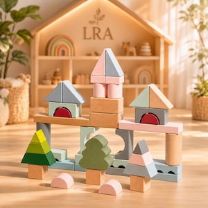 May include: Wooden building blocks in various shapes and colors, including houses, trees, and arches. The blocks are primarily pastel shades of pink, blue, green, and gray, with natural wood tones. The background features a wooden shelf with decorative items.