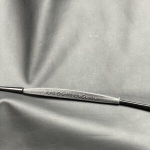 May include: Close-up of a black eyeglass frame with the text "MADE IN U.S.A." printed on the bridge. The frame is made of a matte black material.