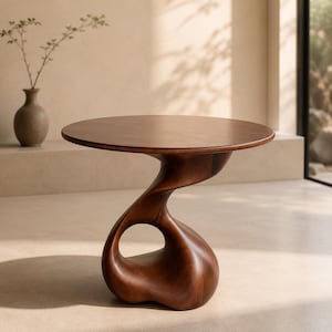 Puede incluir: Una mesa auxiliar redonda de madera con una superficie lisa de color marrón oscuro y una base escultural y fluida con un vacío central. La mesa está hecha de madera maciza con un acabado pulido, mostrando una silueta continua y orgánica.