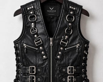 May include: A black leather vest featuring a central zipper, two zippered chest pockets, and two adjustable buckle straps on each side. The front includes silver-toned metal rings and studs. The interior label reads VANCOUR LEATHER BORN BOLDER.