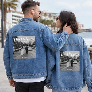May include: Two light blue denim jackets. Each jacket has a black and white photo print on the back, showing a couple walking down a street. The print includes the text "The Heberts" and a date.