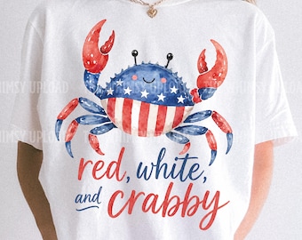 May include: White t-shirt featuring a watercolor crab design in red, white, and blue, with the text "red, white, and crabby." The crab has a blue body with white stars and red and white striped claws and belly. The shirt is paired with red and white checkered shorts.
