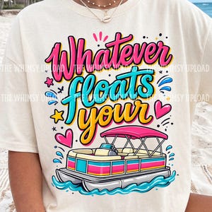 May include: Cream-colored t-shirt with the phrase "Whatever floats your" in a colorful, playful font. A cartoon pontoon boat is featured below the text, with pink, yellow, and blue accents. The shirt has a relaxed fit.