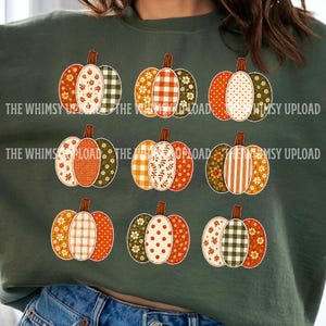 Puede incluir: Una sudadera de cuello redondo en color verde oliva oscuro con un estampado gráfico de nueve calabazas dispuestas en tres filas. Cada calabaza se compone de tres segmentos verticales con patrones variados como flores, cuadros y lunares.