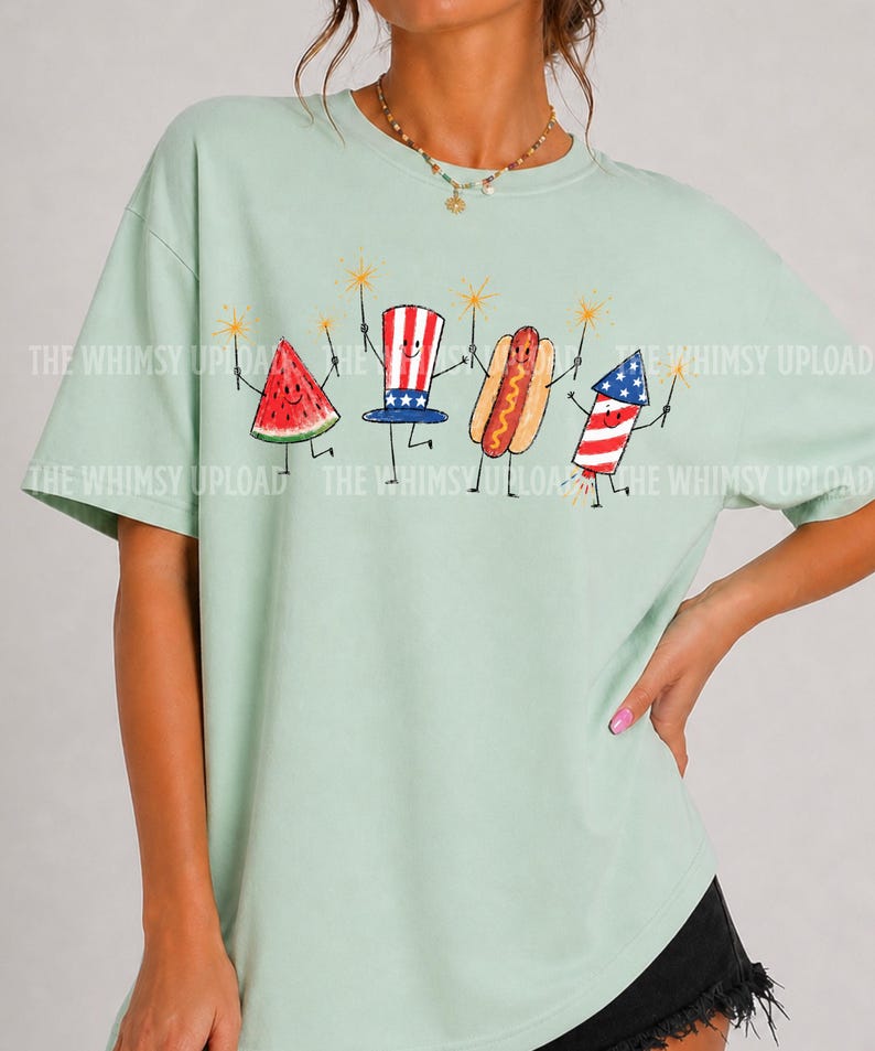 May include: A light green t-shirt featuring a whimsical illustration of a watermelon slice, Uncle Sam hat, hot dog, and firework, each holding a sparkler. The text "THE WHIMSY UPLOAD" is printed on the shirt.