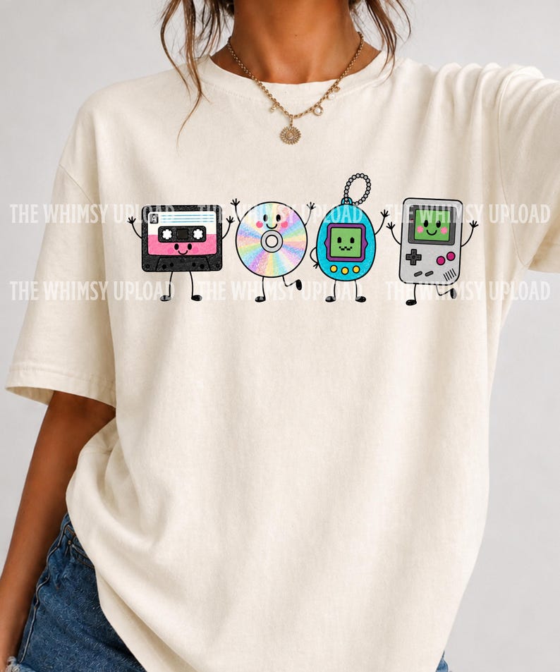 May include: A cream-colored short-sleeve t-shirt featuring a graphic print of four anthropomorphic retro electronics: a pink and black cassette tape, a rainbow-colored compact disc, a blue digital pet, and a grey handheld gaming console.