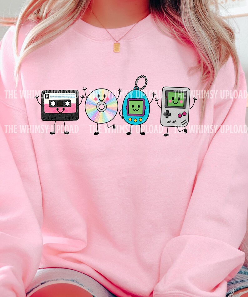May include: A light pink crewneck sweatshirt featuring a graphic print of four anthropomorphic retro electronics: a black cassette tape, a rainbow-colored compact disc, a blue digital pet keychain, and a grey handheld video game console.