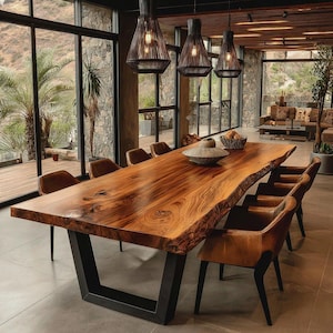 Peut inclure: Une grande table de salle à manger en bois à bord naturel avec une surface au grain brun poli et une base en métal noir en forme de U. La table est entourée de plusieurs chaises en cuir brun à pieds noirs sous trois suspensions en fil noir.