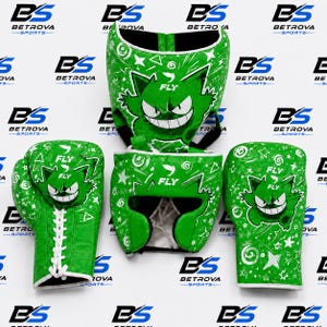 Puede incluir: Un conjunto de equipo de boxeo verde brillante con un gráfico de personaje de dibujos animados blanco con una amplia sonrisa. El set incluye dos guantes de boxeo con cordones y un casco protector, decorados con estrellas, espirales y el texto FLY.