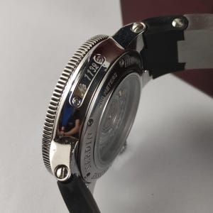 K&ouml;nnte beinhalten: Nahaufnahme einer silbernen Armbanduhr mit schwarzem Armband. Auf dem Zifferblatt steht "200 METERS" und "NARDIN". Die Uhr hat eine geriffelte L&uuml;nette und die Nummer "1132" ist sichtbar.