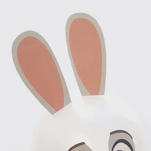 May include: A whimsical illustration of a bunny face with two upright ears. The ears are light pink inside with a gray border, and the face is white. The eyes are gray and black.