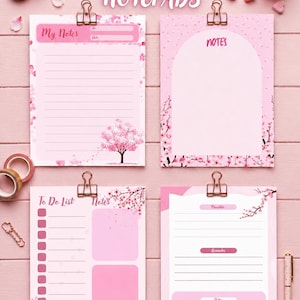 Könnte beinhalten: Vier druckbare Notizblöcke mit rosa Kirschblütenmotiven. Die Blätter enthalten Abschnitte mit der Beschriftung My Notes, Notes, To Do List und Priorities. Jeder Block wird von einer Metallklammer gehalten und zeigt linierte Bereiche, Checkboxen und florale Illustrationen auf einem hellrosa Holzuntergrund.