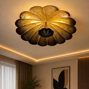 Peut inclure: Un plafonnier décoratif en forme de pétale. Le luminaire a une finition bronze foncé avec une lueur dorée et chaleureuse. La lumière est montée sur un plafond blanc. Un élément décoratif.