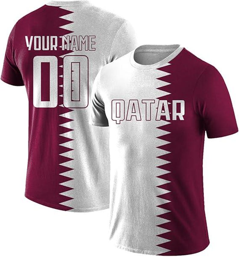 May include: Two white and maroon t-shirts. One shirt has "QATAR" printed on the front. The other shirt has "YOUR NAME" and the number "00" printed on the back. The shirts have a zig-zag design that splits the shirt in half.