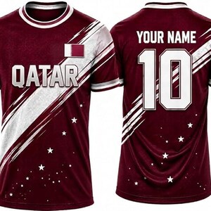 May include: Maroon soccer jersey with white accents and the word "QATAR" across the chest. The jersey features the Qatar flag and a white stripe design. The back displays the number 10 and the text "YOUR NAME".