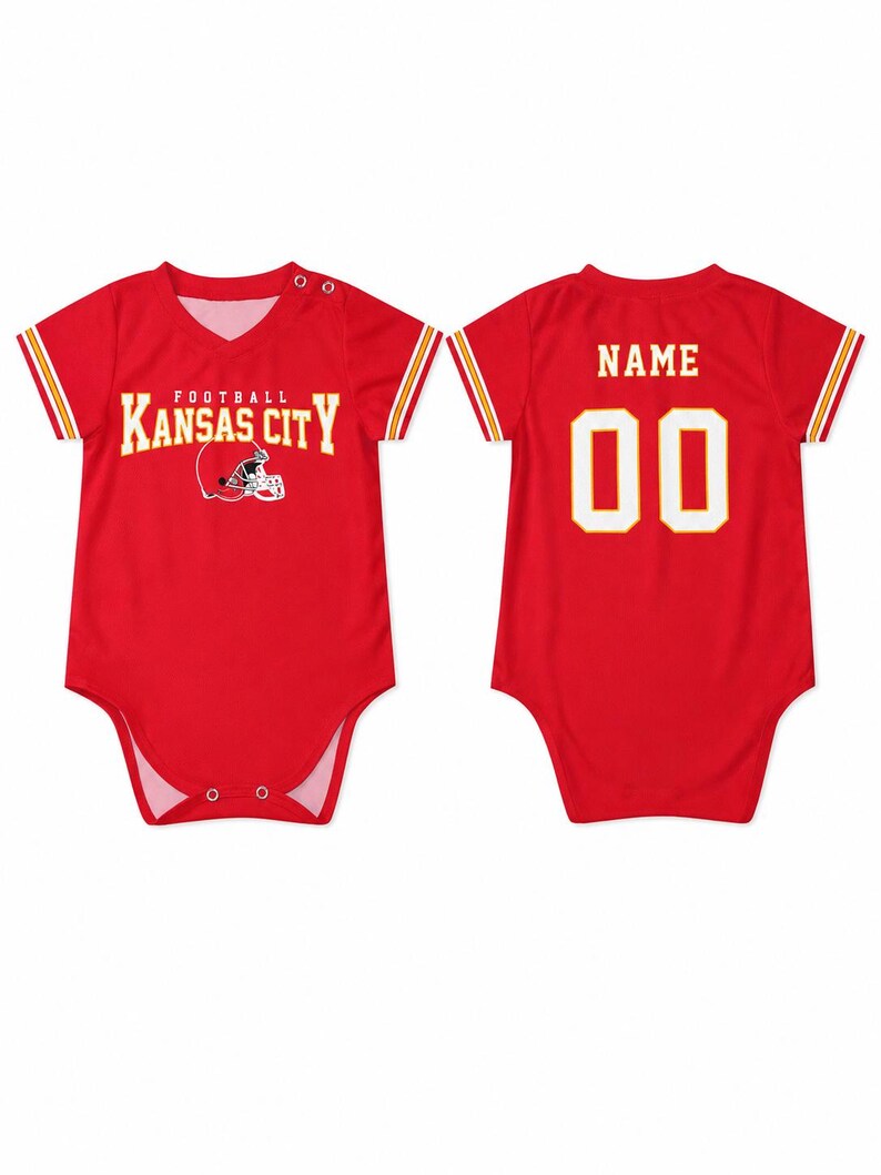May include: A red short-sleeved baby bodysuit featuring the text KANSAS CITY FOOTBALL and a helmet graphic on the front. The back displays the word NAME and the number 00 in white lettering. The sleeves have yellow and white stripes.